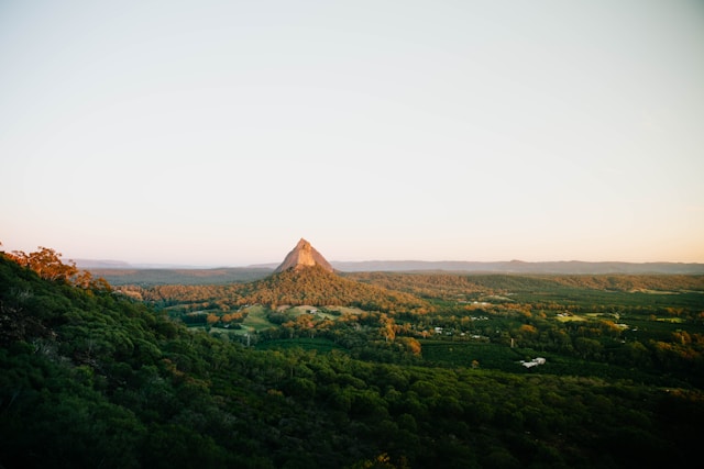 The Glass House Mountains in Queensland, showcasing lush green landscapes and a prominent volcanic peak under a clear sky.